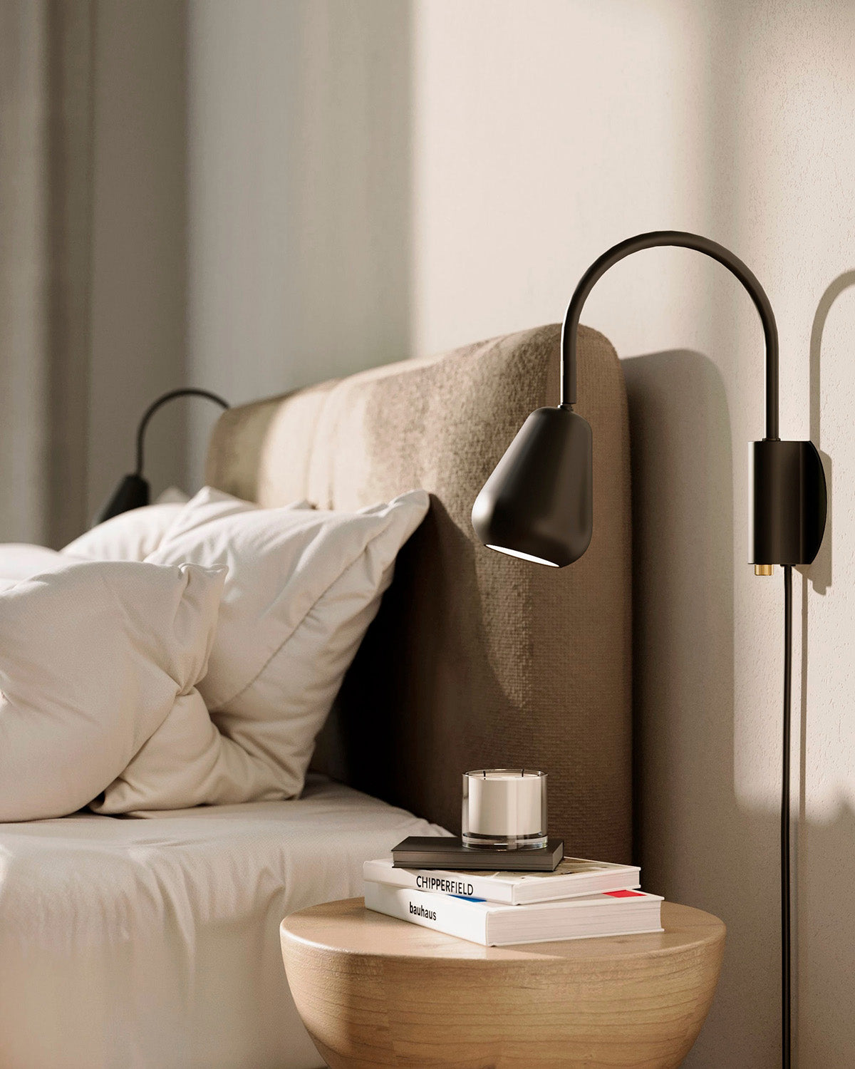 Anoli Spot Wall is a modern wall lamp and is ideal next to a bed styled with books and a candle on a nightstand.