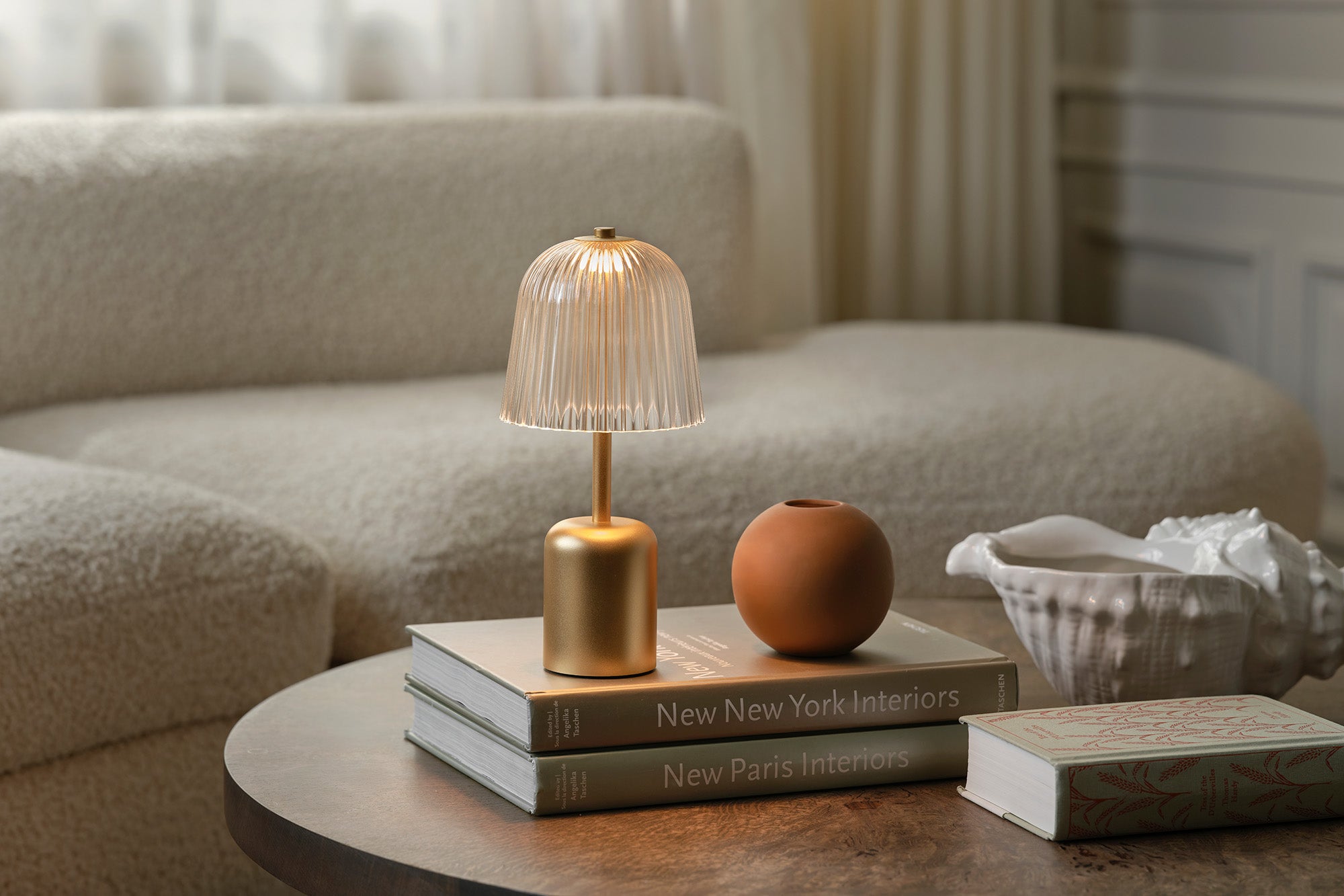 Asteea Table as decorative lamp on books with a vase and tissue box on a coffee table in a living room.