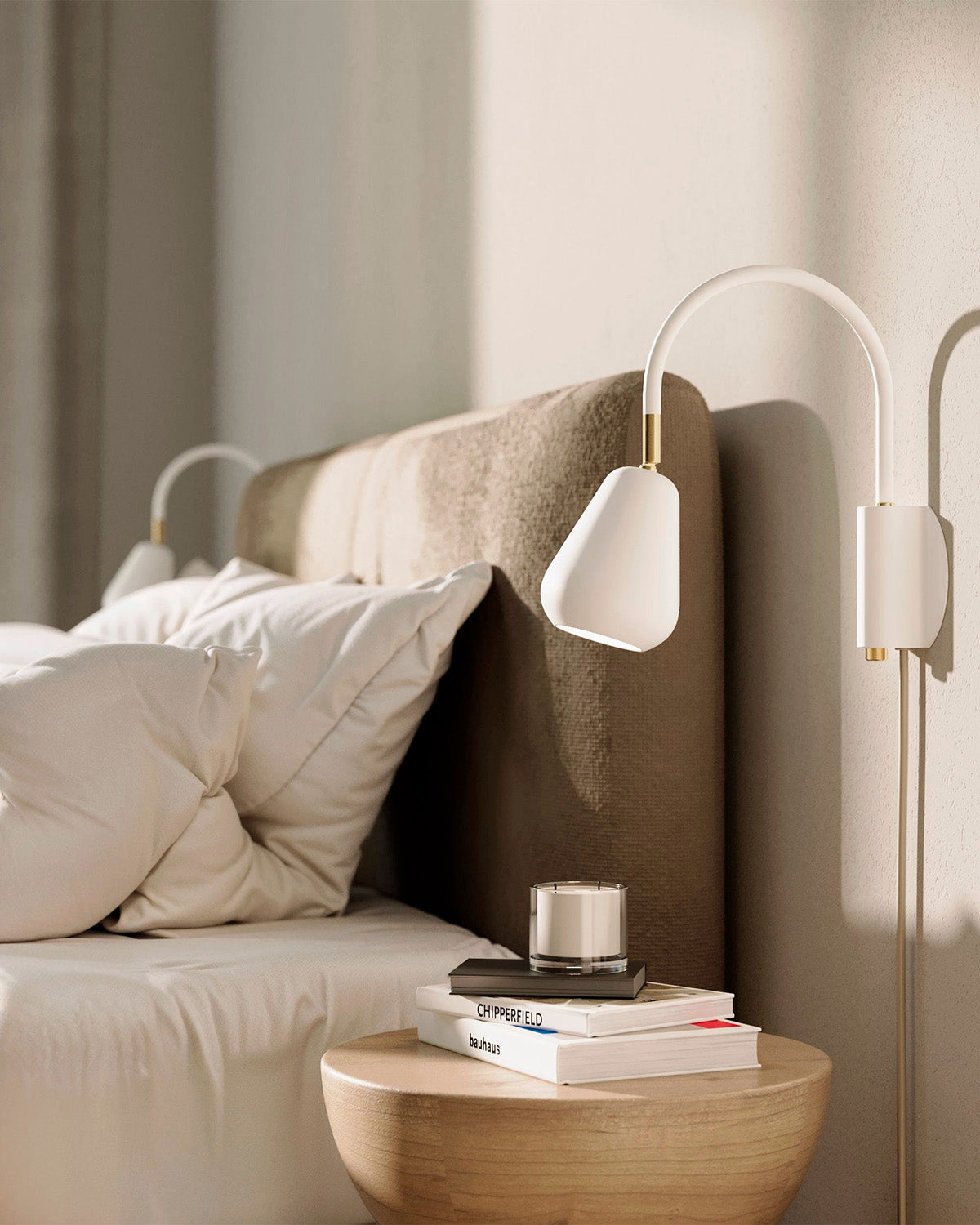 Anoli Spot Wall closeup of Wall-mounted lamps next to a bed with books and a candle on a nightstand.